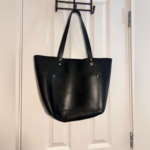 Black leather tote bag with gold hardware, featuring a large pocket